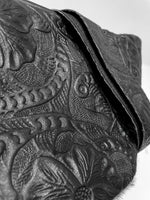 Close-up of the back of the black cow hair leather fanny pack showing detailed leather engraving flowery patterns. 