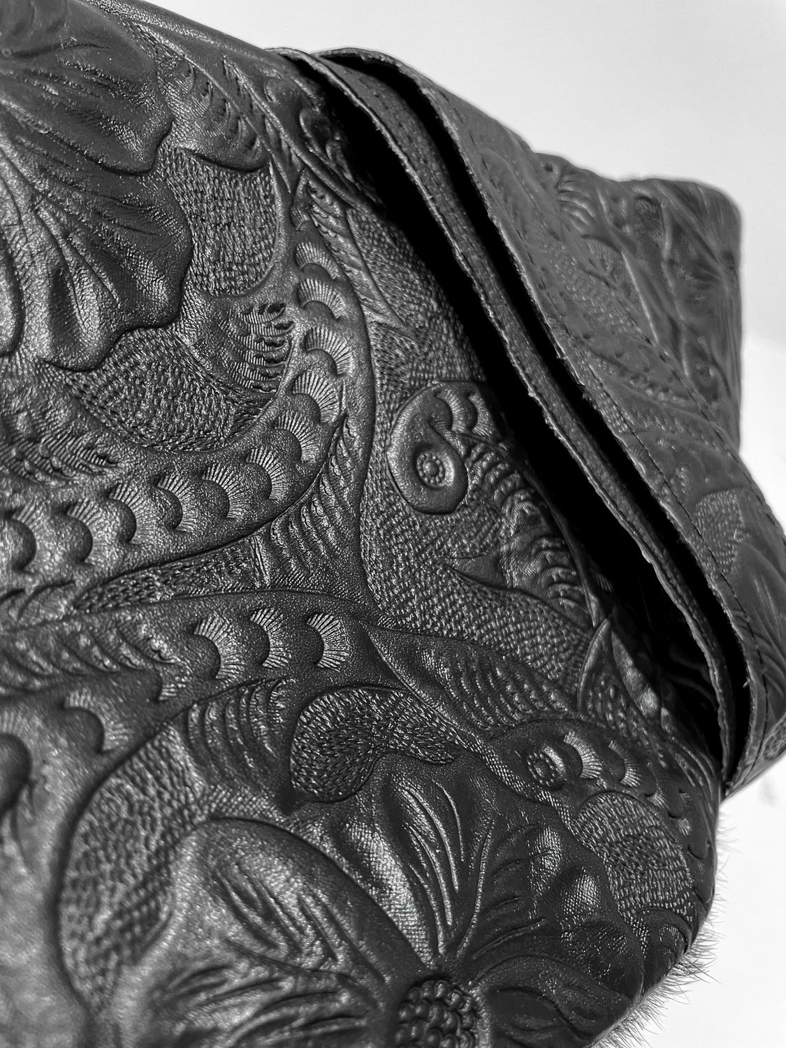 Close-up of the back of the black cow hair leather fanny pack showing detailed leather engraving flowery patterns. 