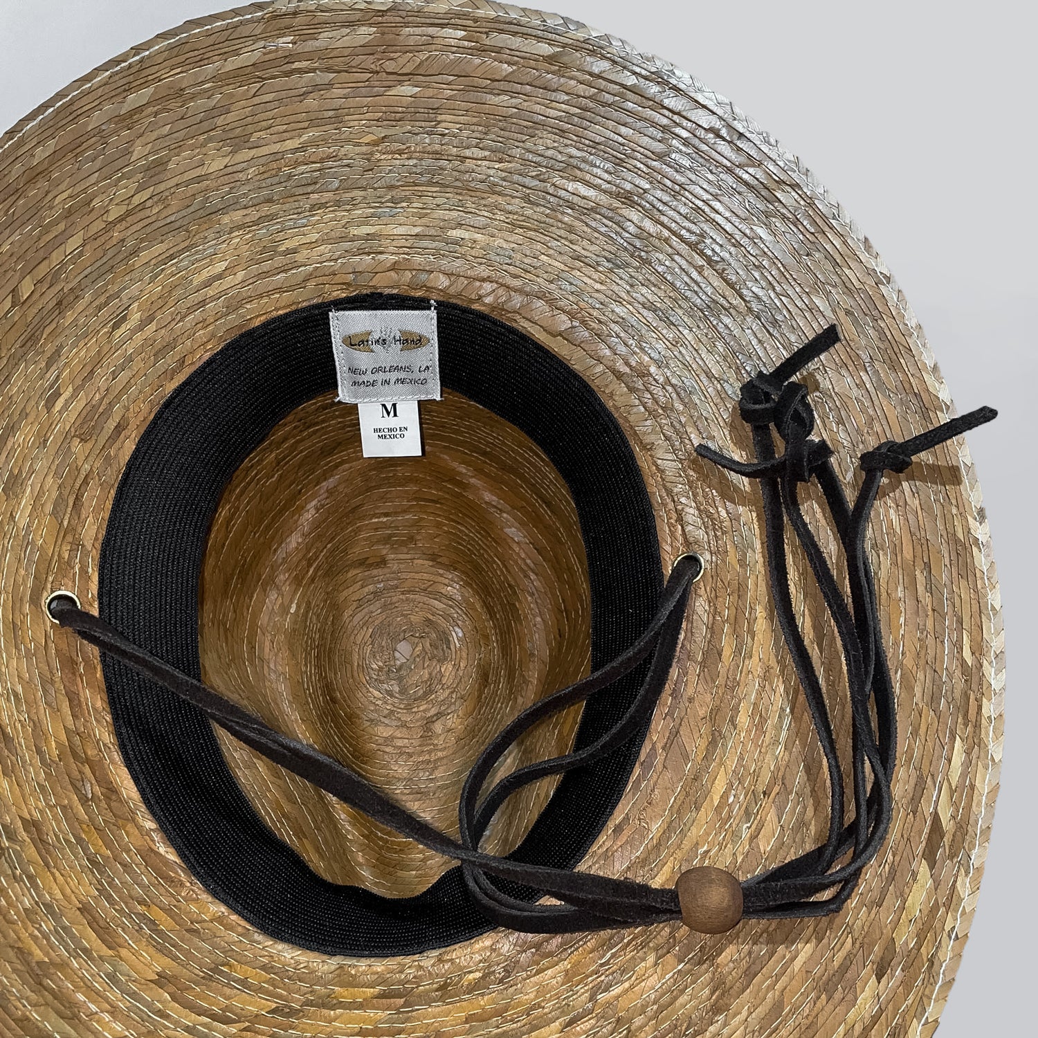 Closeup of inside the palm straw safari hat, showing the stretchy cotton band and Latin's Hand tag