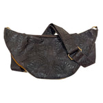 Back of brown cow hair leather fanny pack showing adjustable tooled leather strap and gold-tone hardware. 