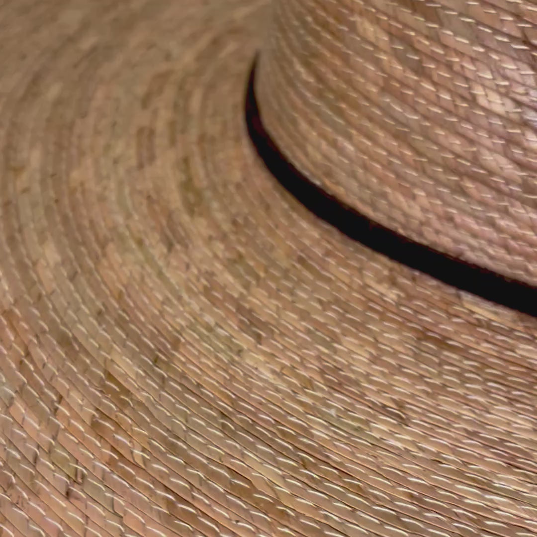 Video closeup and pan back displaying the handwoven palm leaf straw of the Indiana Adventure Hat and leather chin strap and the holes / eyelets on the sides of the crown